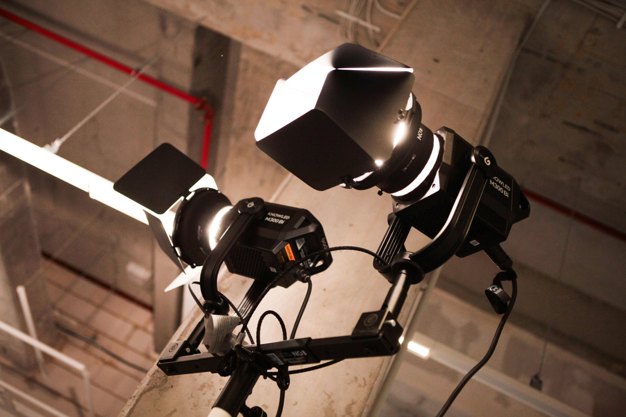 Professionelle KNOWLED M300Bi LED-Studiolichter auf Rig montiert in einer industriellen Event-Location.