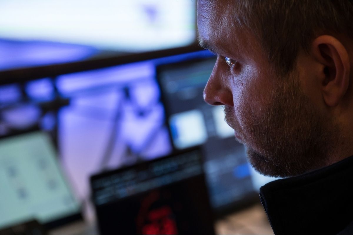 Konzentrierter Medientechniker überwacht mehrere Bildschirme mit Streaming- und Event-Technik in einem Kontrollraum.