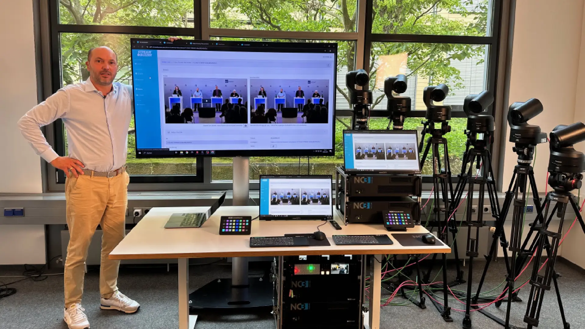 Marc Ilgner von NC3 steht vor einem professionellen Streaming-Setup mit PTZ-Kameras, Monitoren und Steuerungseinheiten für Live-Events.