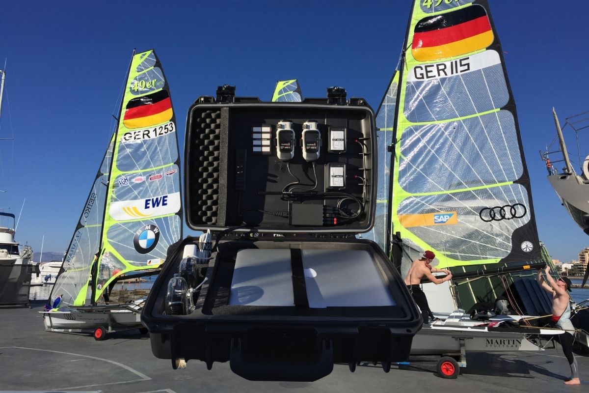 Offenes Equipment-Case mit GPS-Recording-Geräten vor Segelbooten mit deutscher Flagge beim SAP Sailing Event